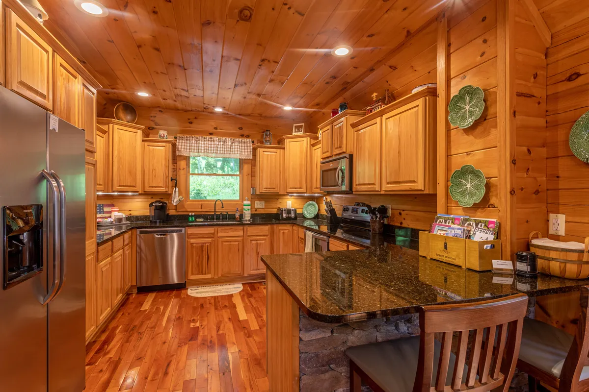 A spacious kitchen with a central island, stainless steel appliances, wooden cabinetry, and green decorative plates. The layout is inviting, offering plenty of room for cooking, socializing, or enjoying family time together.