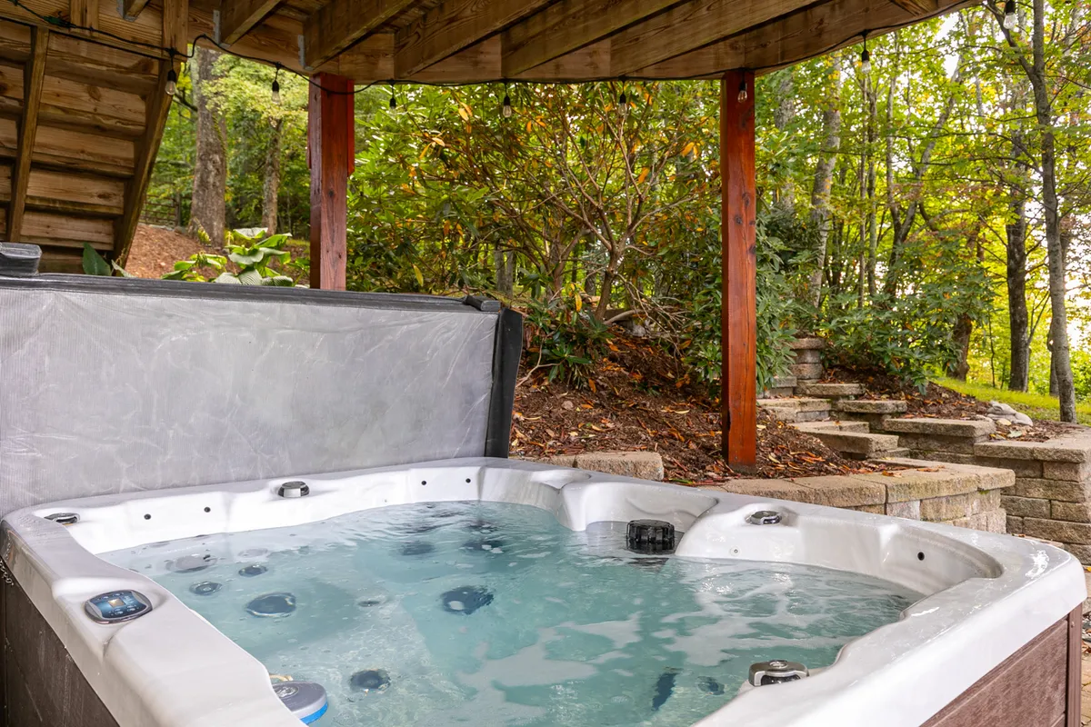 This image shows a bubbling hot tub nestled outdoors, surrounded by lush greenery and stone steps. The natural setting evokes relaxation and socializing, offering a picturesque spot to unwind after a day of exploring nearby attractions.