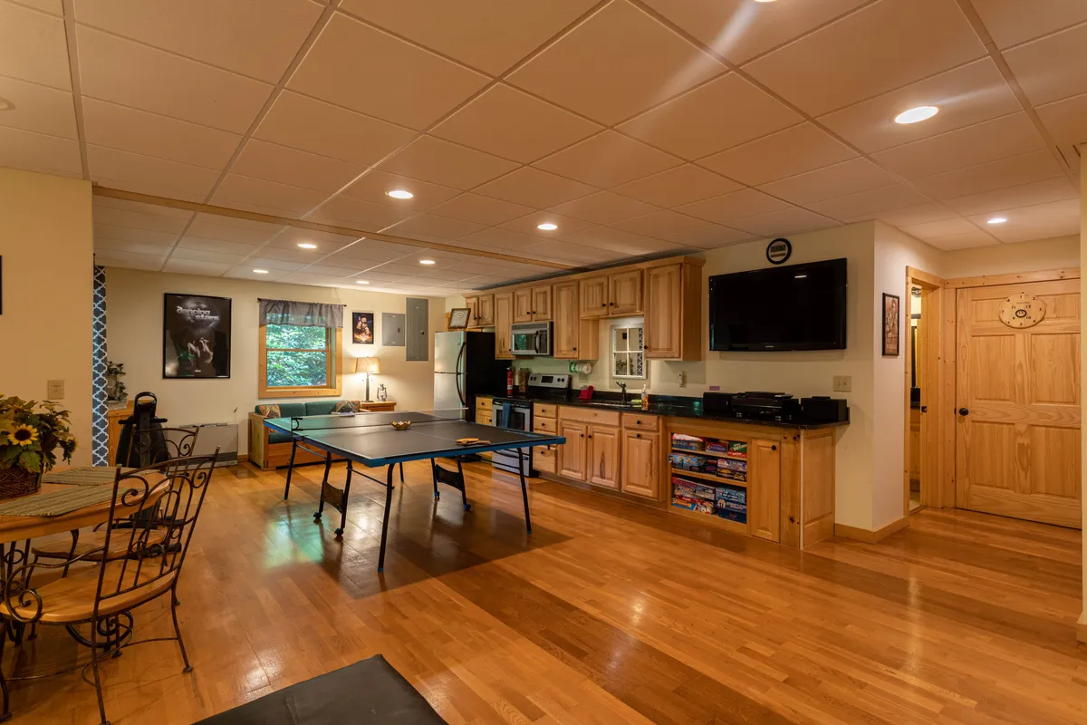 An interior shot centered on a ping pong table with a kitchen and dining area in the background. The space is lively and friendly, with a relaxed atmosphere ideal for social games and casual gatherings.